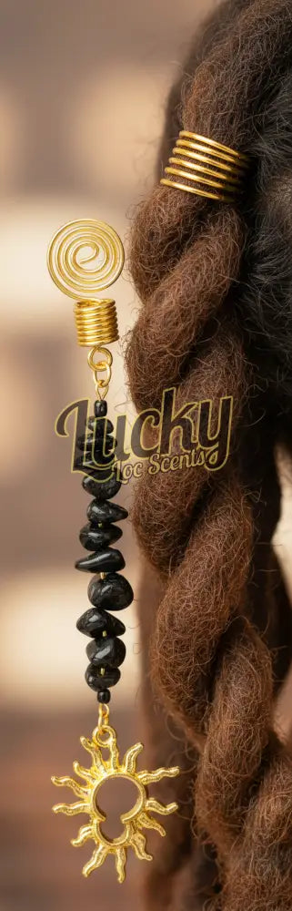 Decorative charm with black stones. Gold spiral design and gold sun